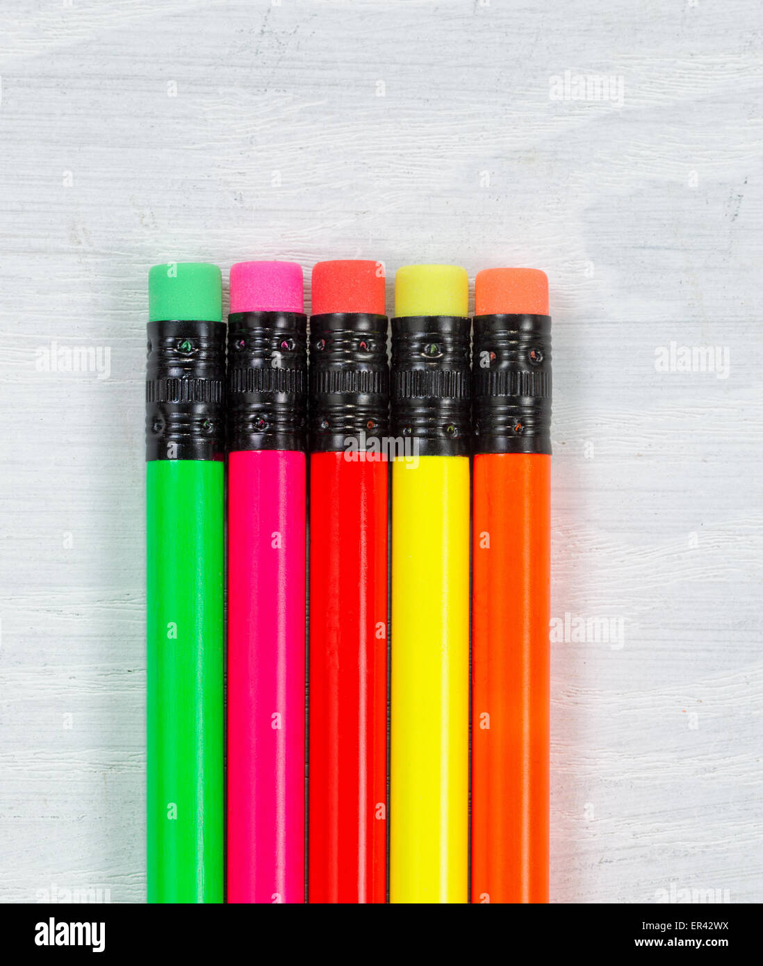 Close up of colorful pencil tip erasers on white desktop. Layout in vertical format. Stock Photo