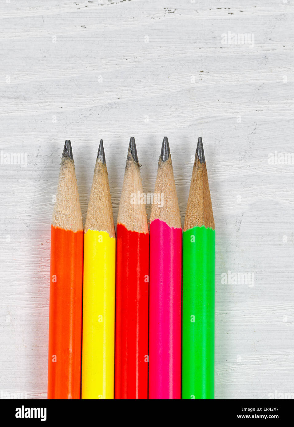 Close up of colorful sharpen pencil tips on white desktop. Layout in vertical format. Stock Photo