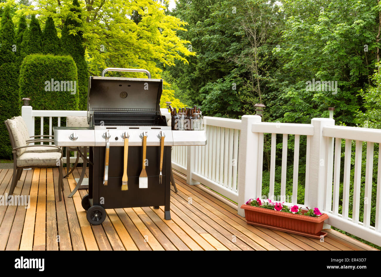 Photo of a clean barbecue cooker with cookware and cold beer in bucket on cedar wood patio. Stock Photo
