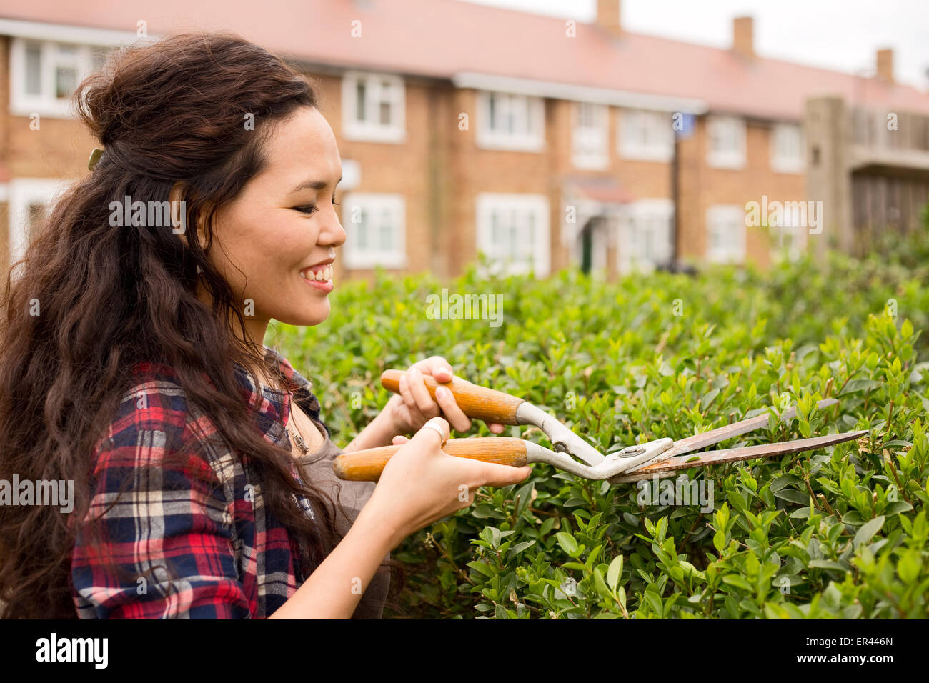 young woman cutting her hedge Stock Photo