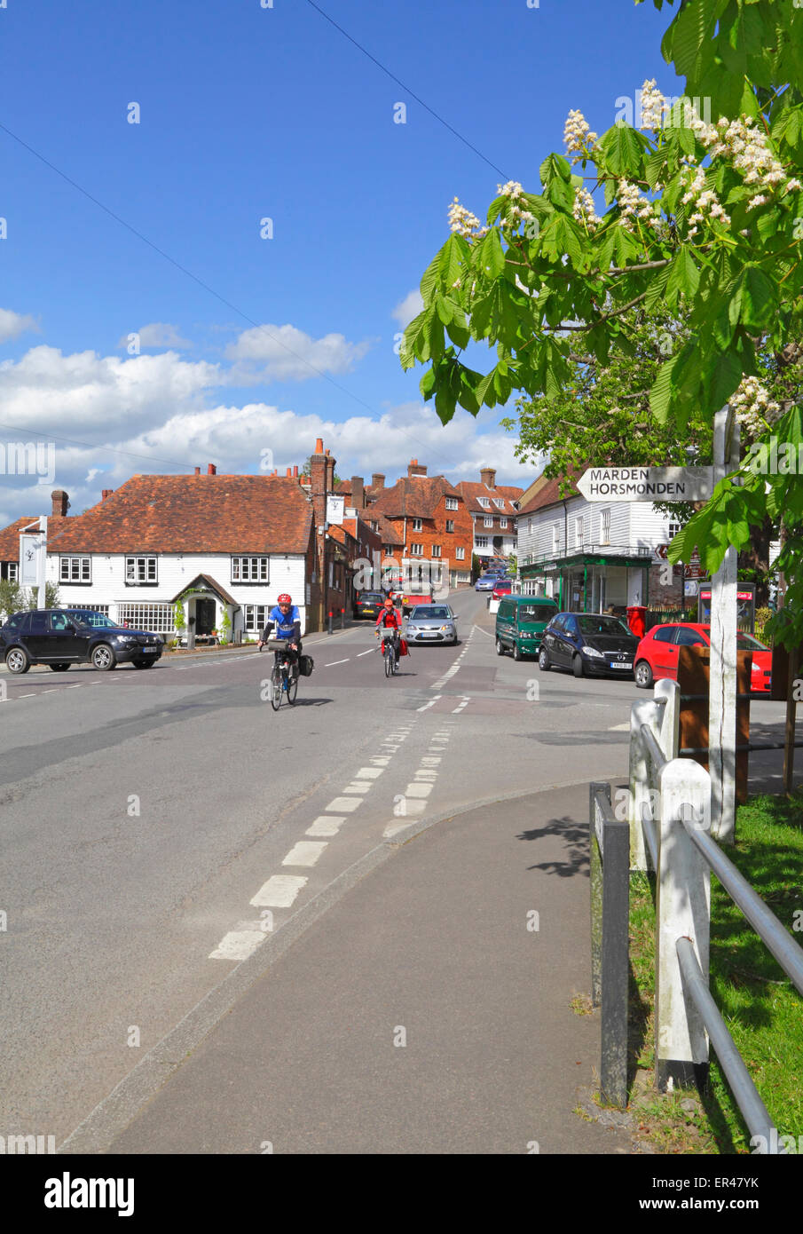 Two cyclists cycling through the pretty Wealden village of Goudhurst. Kent, England, UK Stock Photo