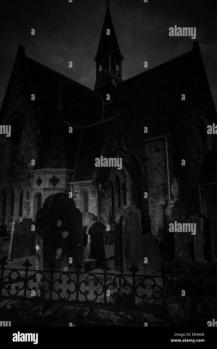 Night time at Luss Village Parish Church, Argyll & Bute, Scotland and gravestones are illuminated by street light. Stock Photo