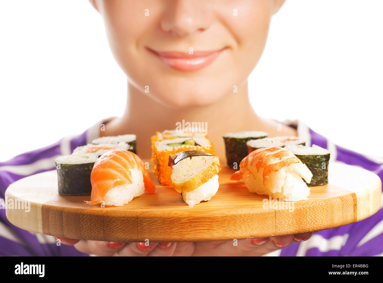 Happy woman holding bamboo plate with fresh sushi set on it (Shallow DoF, focus on sushi) Stock Photo