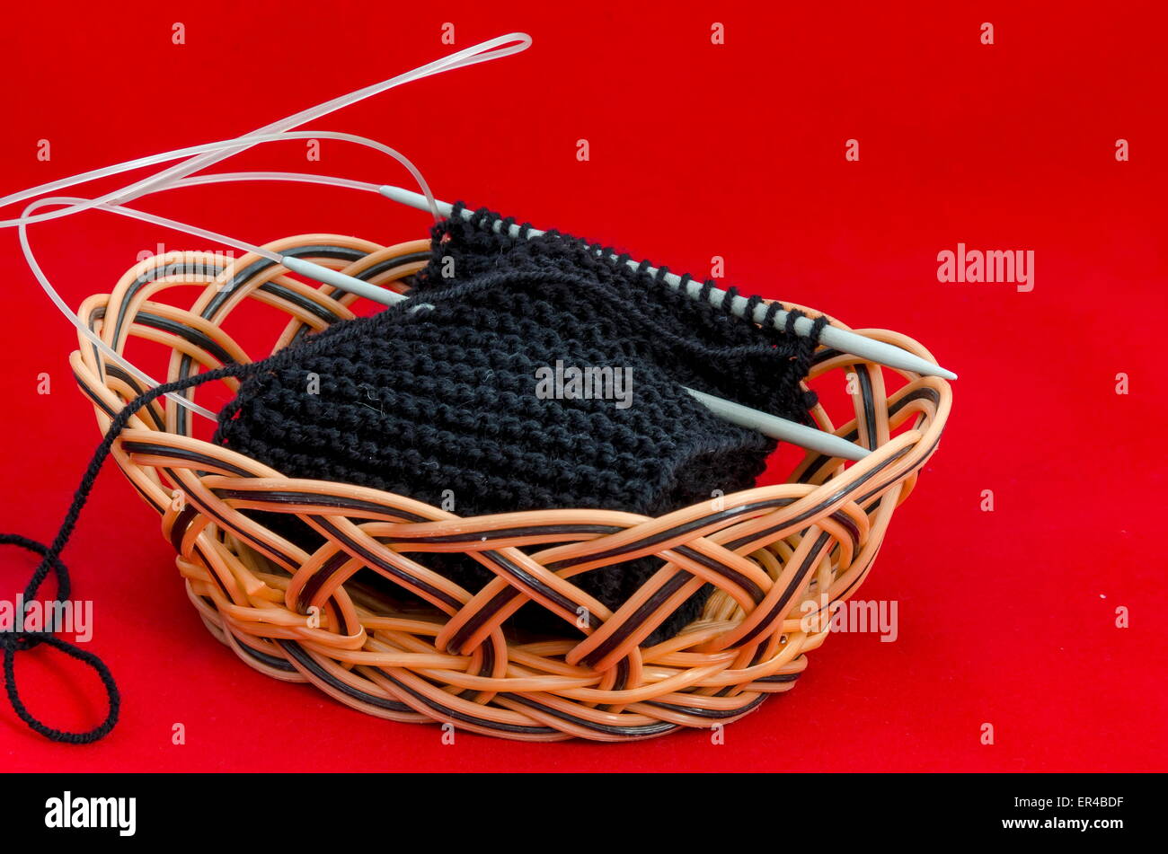 Stitch with knitting-needle in small basket - orange background Stock Photo