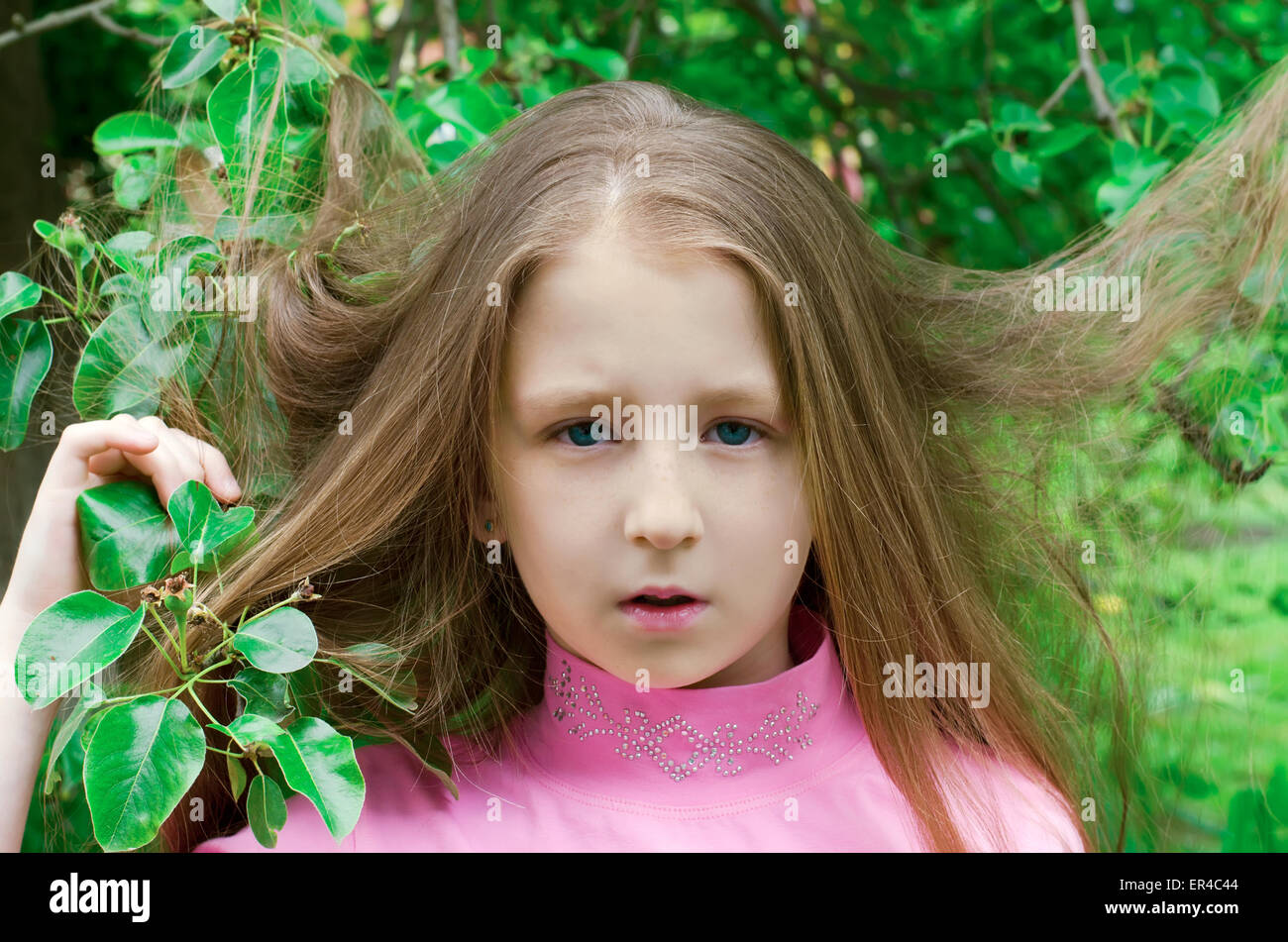 nice little girl costs near a tree in the summer Stock Photo - Alamy