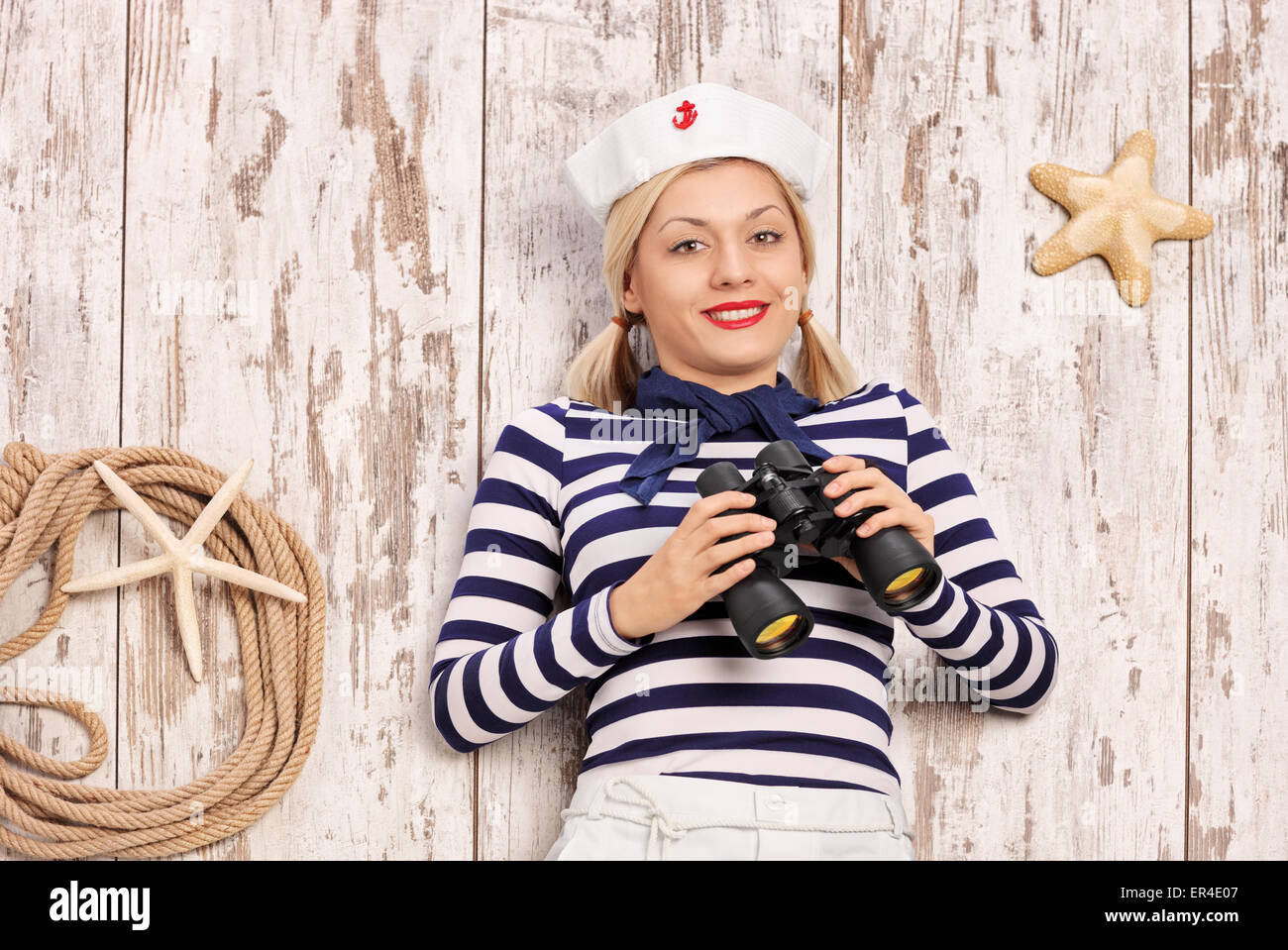 Female sailor lying on a deck with binoculars in her hand and looking ...
