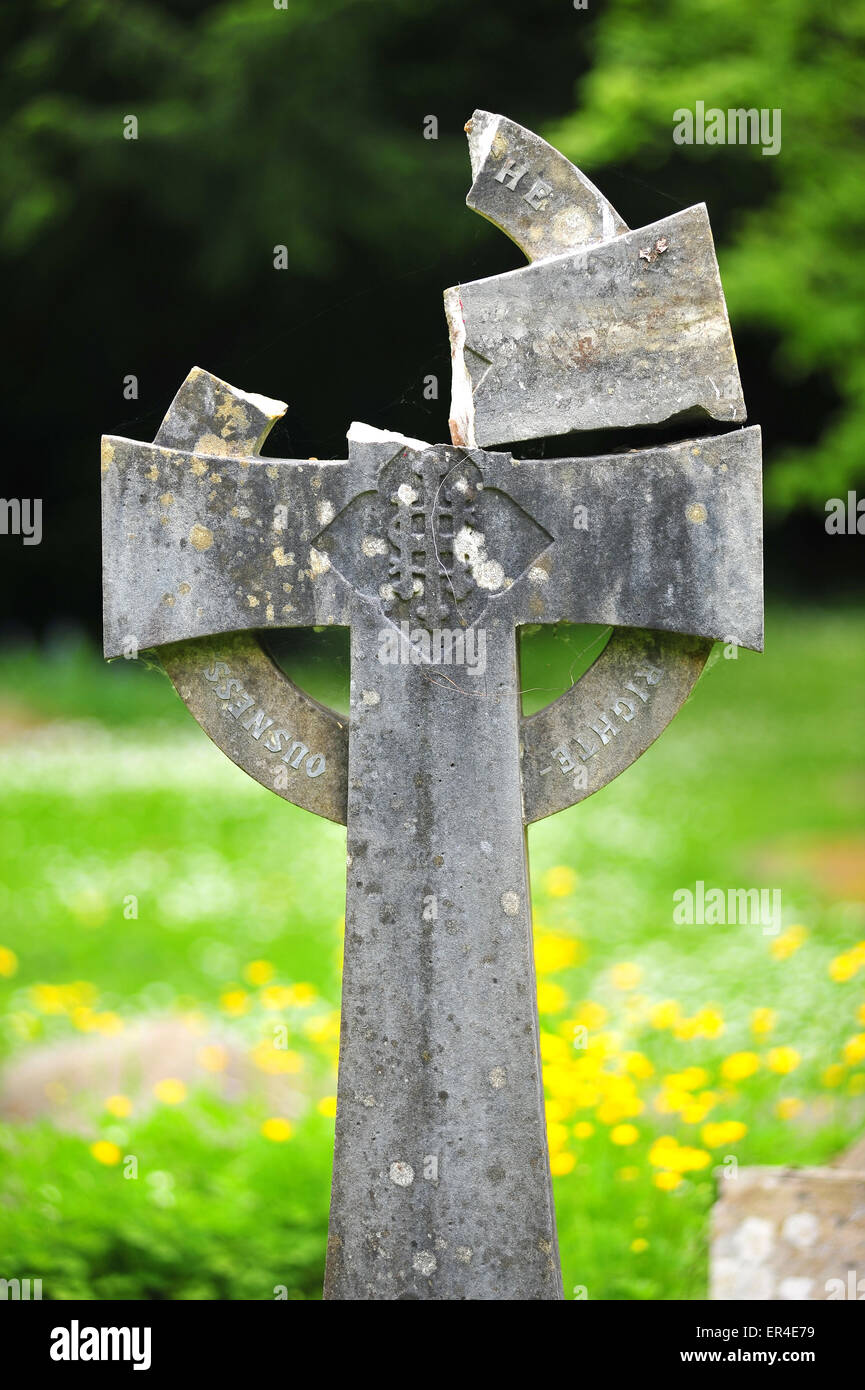 A broken stone cross tombstone in a graveyard along Birdcage Walk in Bristol. Stock Photo