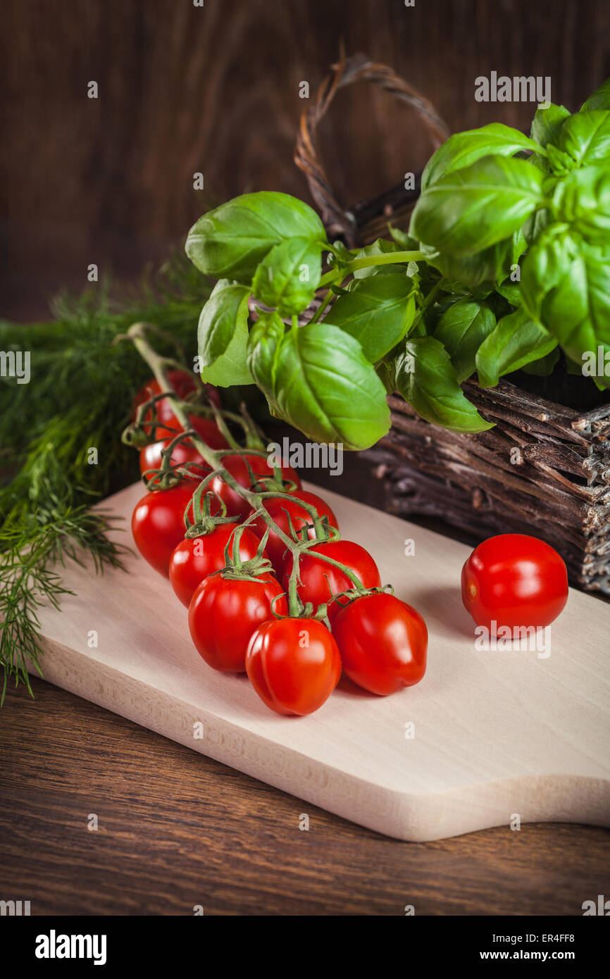 Tomatoes and herbs in a basket Stock Photo - Alamy