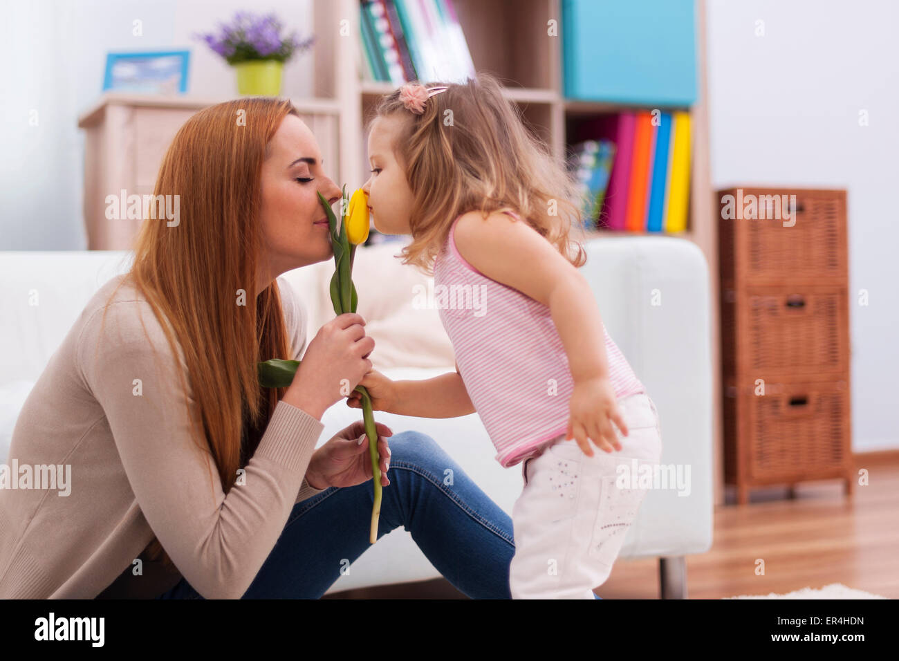 Cute little girl with her mother smelling fresh tulip. Debica, Poland Stock Photo