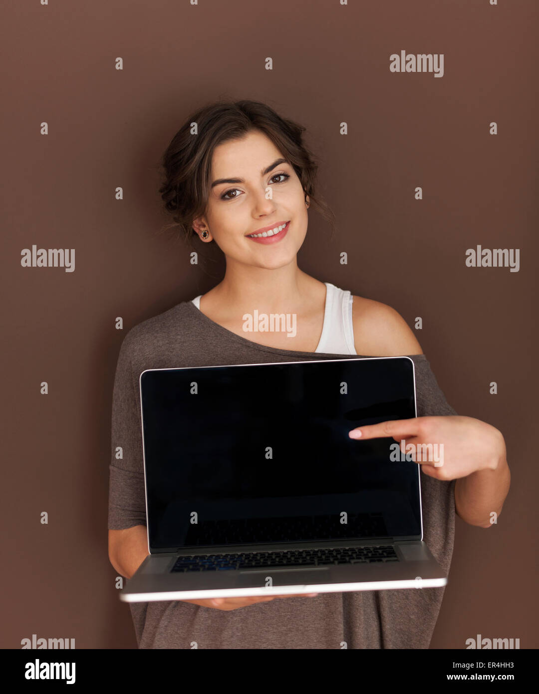 Beautiful woman pointing to caption space on laptop Stock Photo