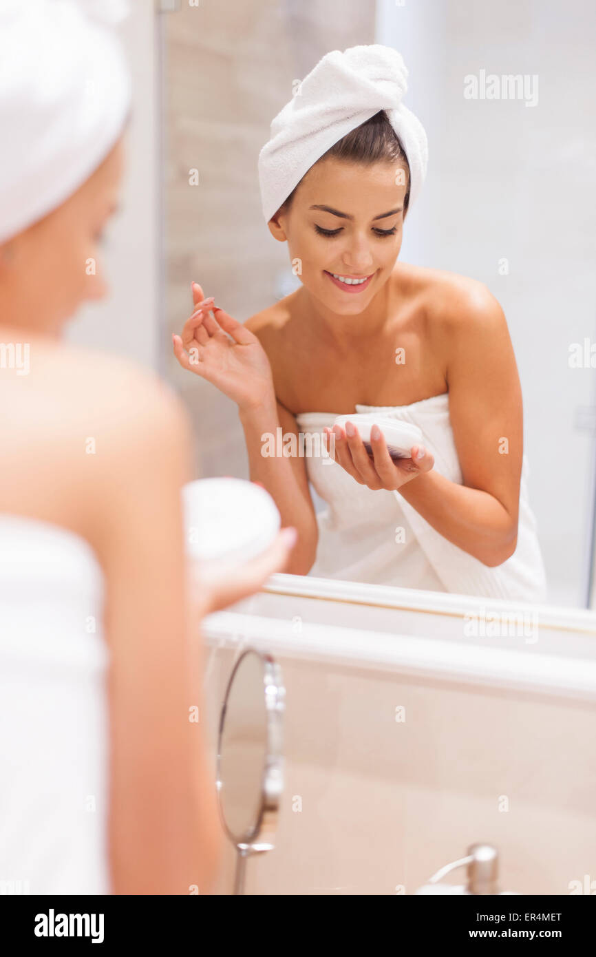 Smiling woman moisturizes skin after the shower. Debica, Poland Stock Photo