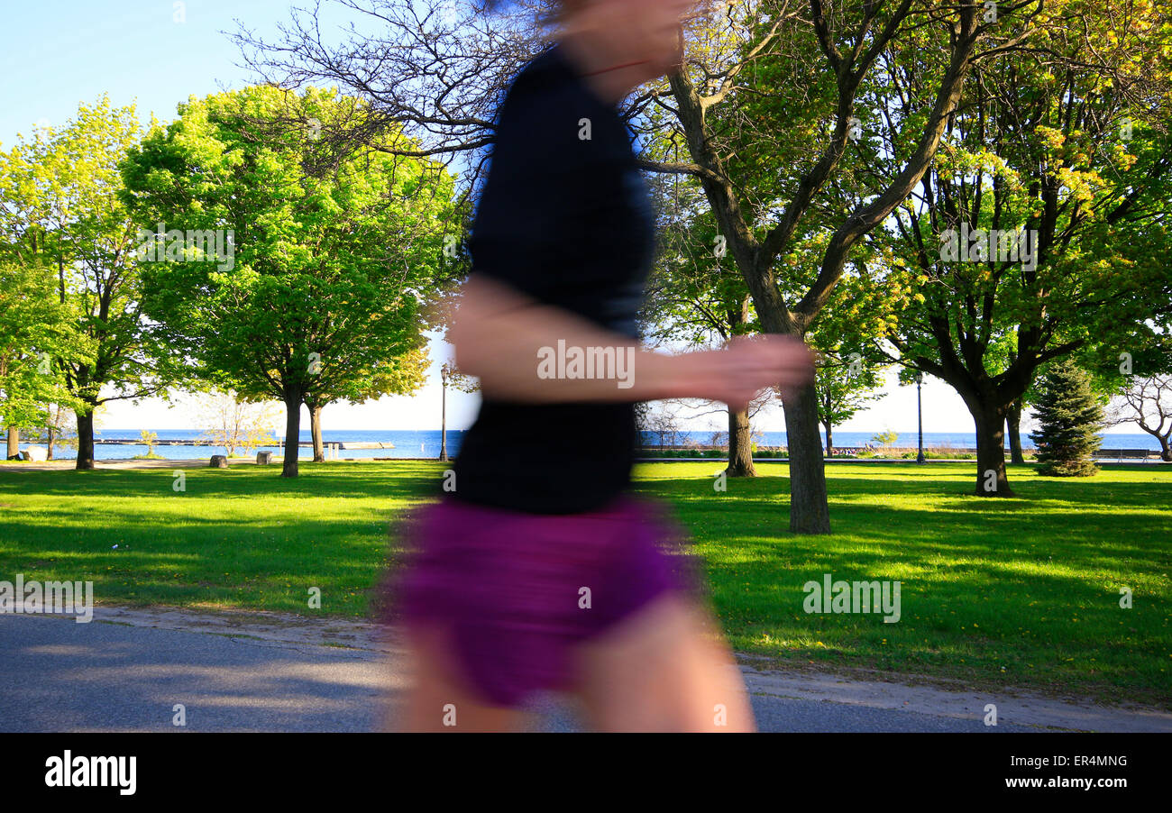Motion blurred and unrecognizable middle section of female body running on waterfront trail near Humber Bay in Toronto Stock Photo