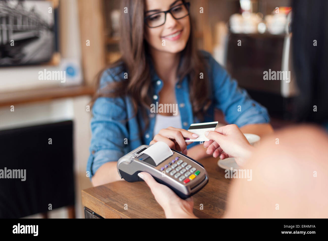 Smiling woman paying for coffee by credit card. Krakow, Poland Stock Photo
