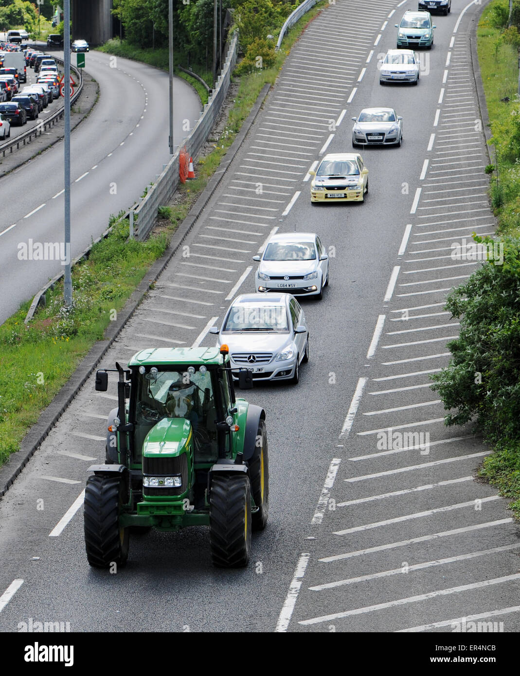 Slow moving farm tractor causes traffic congestion with tail back of cars behind on the road Stock Photo
