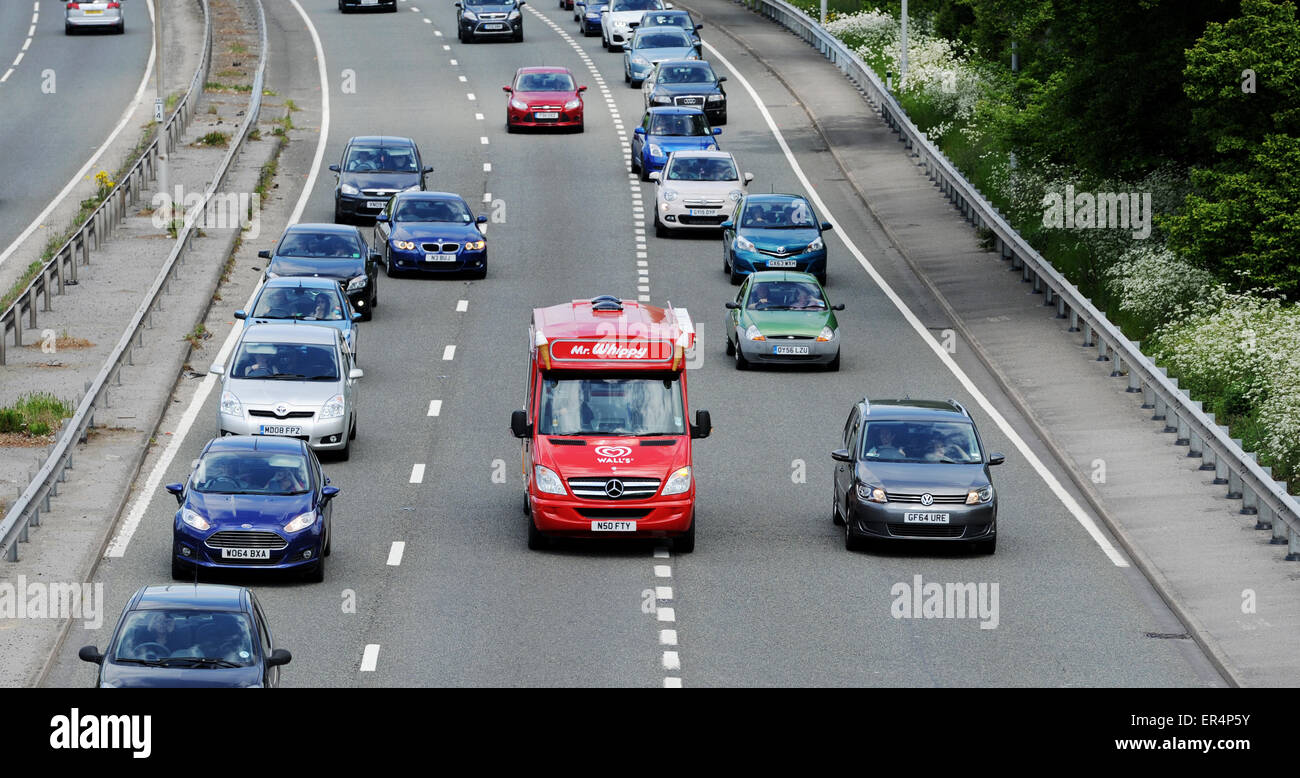 Bright red Walls Mr Whippy Ice Cream van on the road amongst traffic