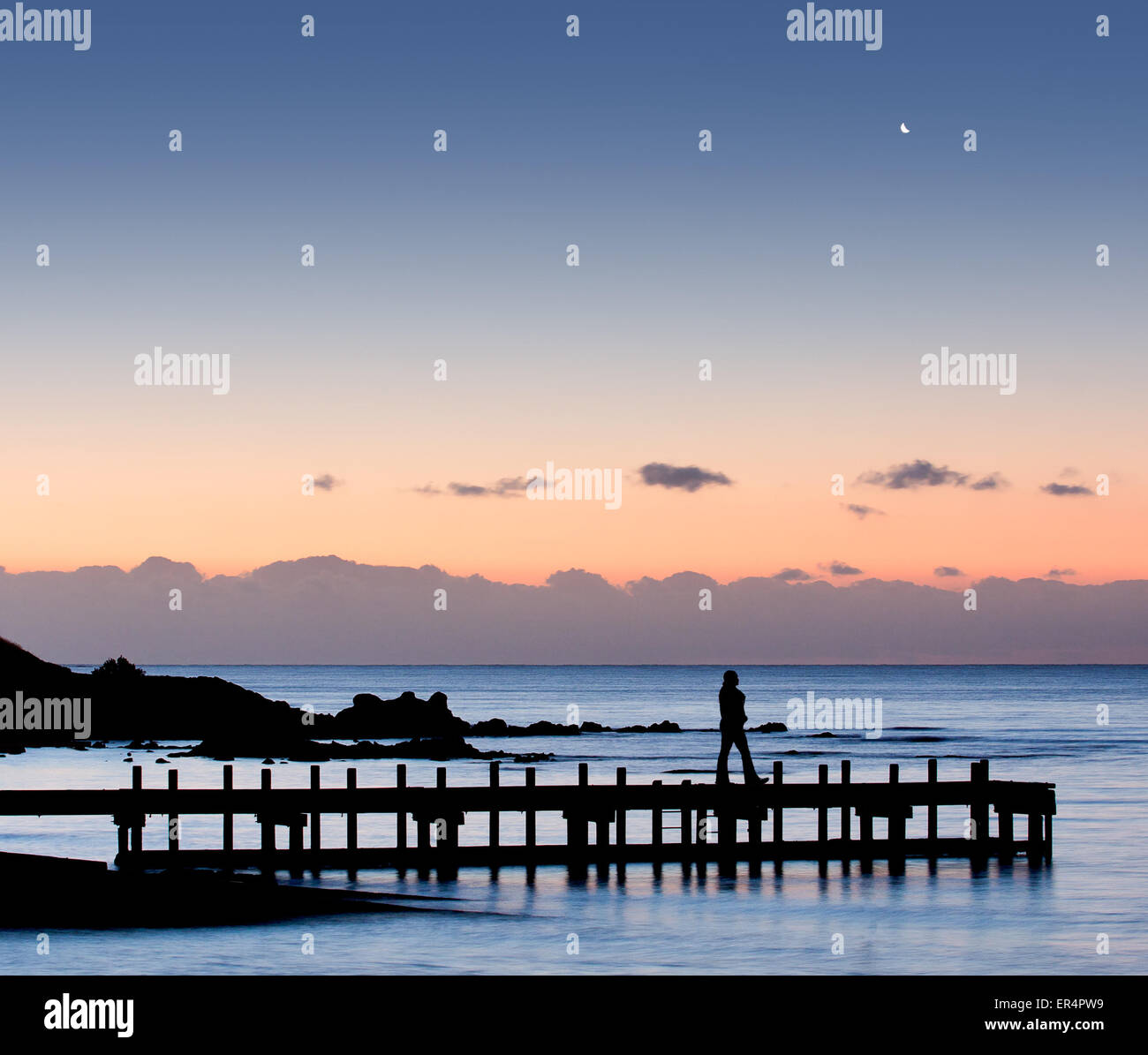 Silhouette of a woman walking on pier with moon in the sky Stock Photo ...