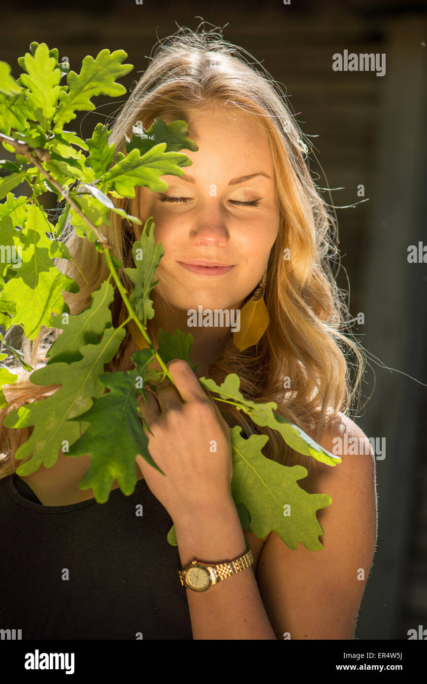Blond young woman and branch of oak tree Stock Photo