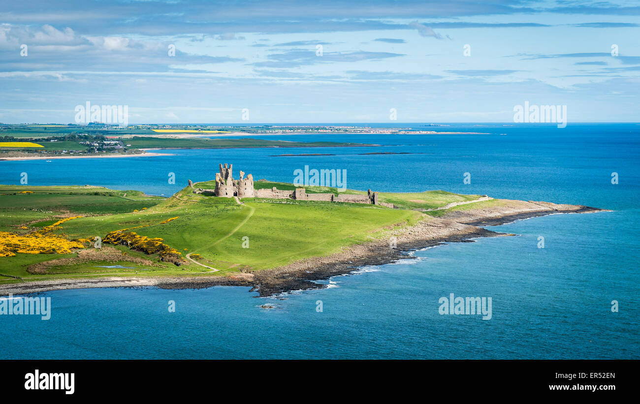 Dunstanburgh Castle with Bamburgh Castle in the background, Northumberland, UK Stock Photo