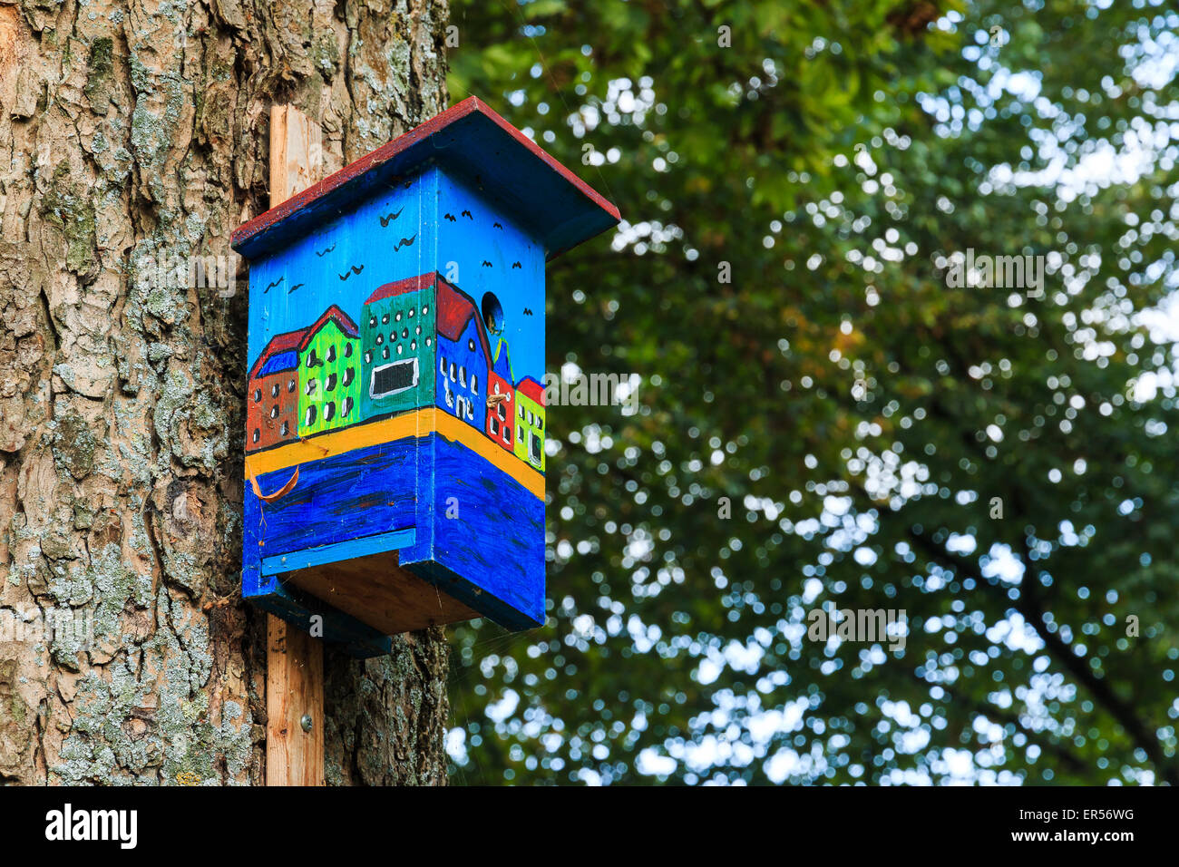 Colorful birdhouse showing canal houses in Amsterdam. Side view showing leafs tree in unsharp background. Stock Photo