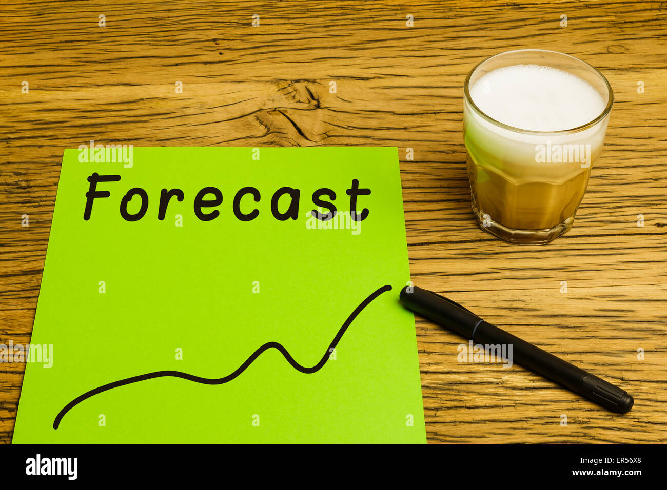 Forecast written on green paper with graph. Marker and coffee on desk. Stock Photo