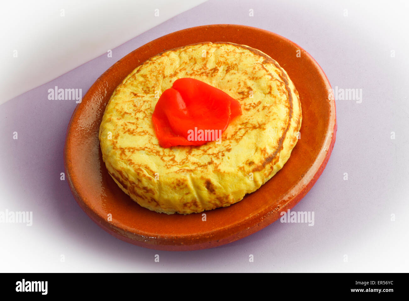 Spanish omelette and pepper on white and purple background Stock Photo