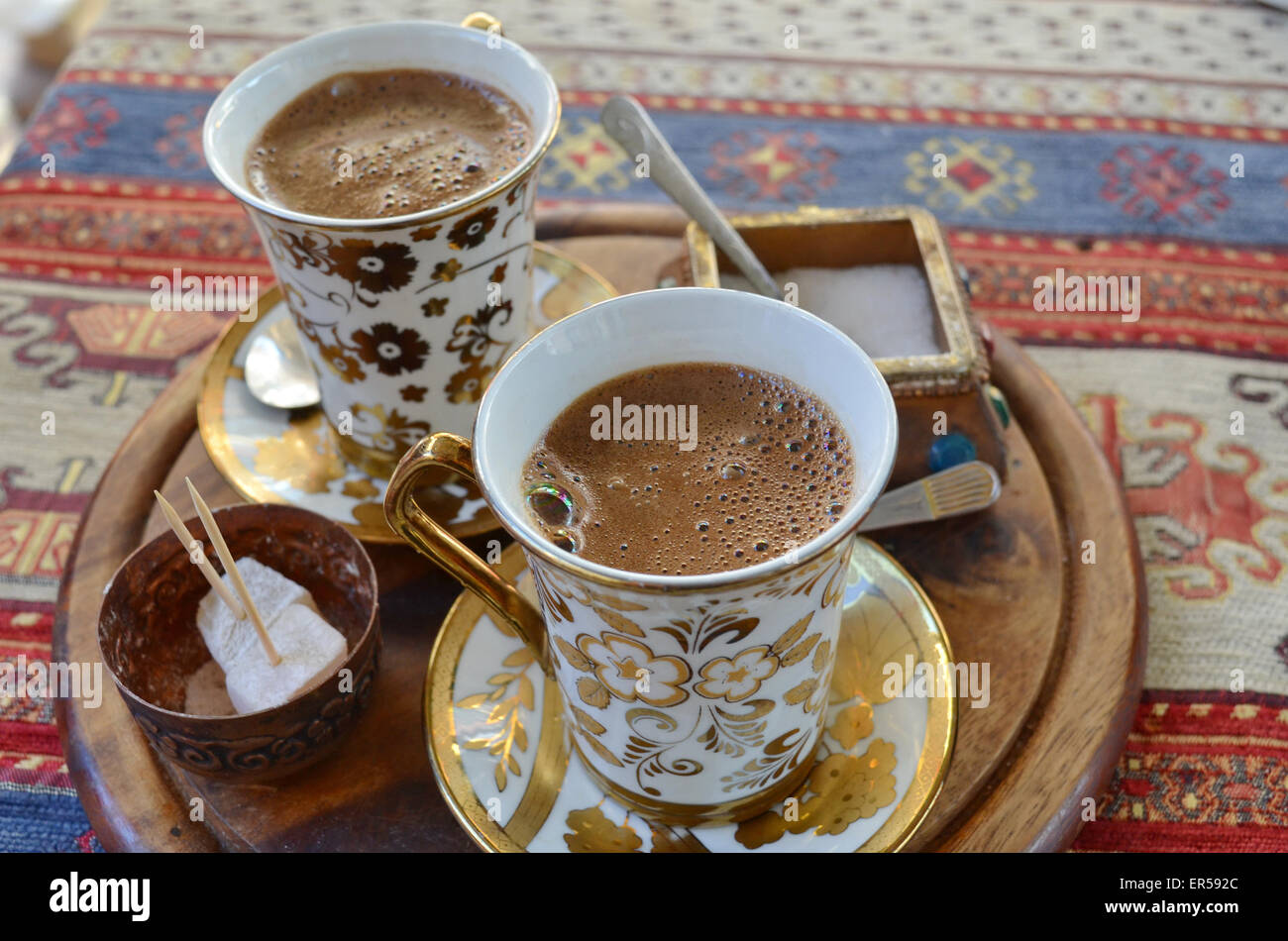 Two cups of Turkish coffee on wooden tray placed upon a colorful rug Stock Photo