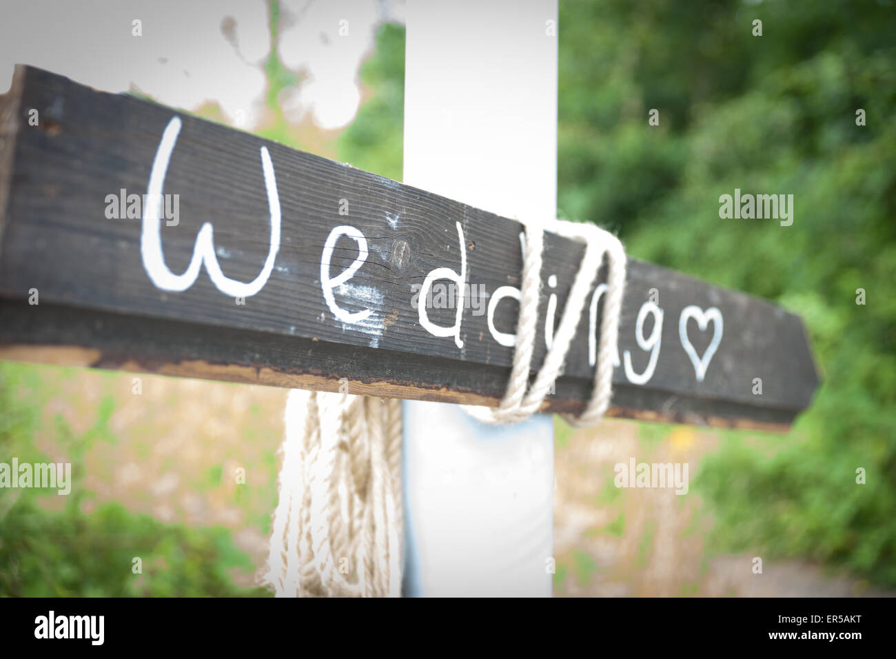 Grey wooden arrow sign with Wedding and a heart written on it in chalk Stock Photo