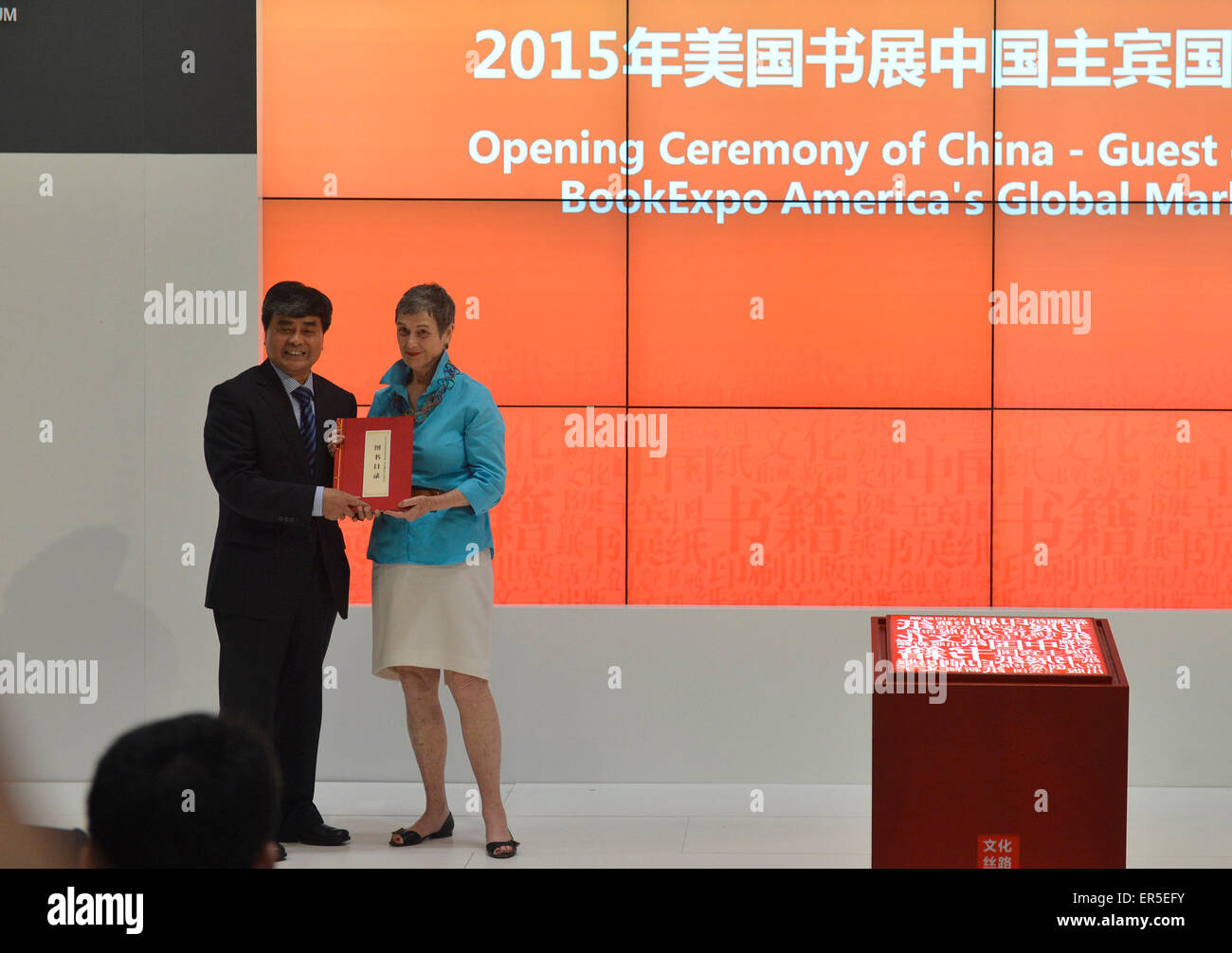 (150527) -- NEW YORK, May 27, 2015 (Xinhua) -- Wu Shangzhi(L), vice minister of China's State Administration of Press, Publication, Radio, Film and Television, gives a book as gifts to Kristin Mc Daught, a representitive from New York Public Library during the opening ceremony of China-Guest of Honor 2015 BookExpo America's Global Market Forum in New York, the United States, on May 27, 2015. Bringing in nearly 10,000 book titles from some 150 publishers, China came under the spotlight in this "publishing and cultural capital of the world" as BookExpo America (BEA) 2015 kicked off in New York C Stock Photo