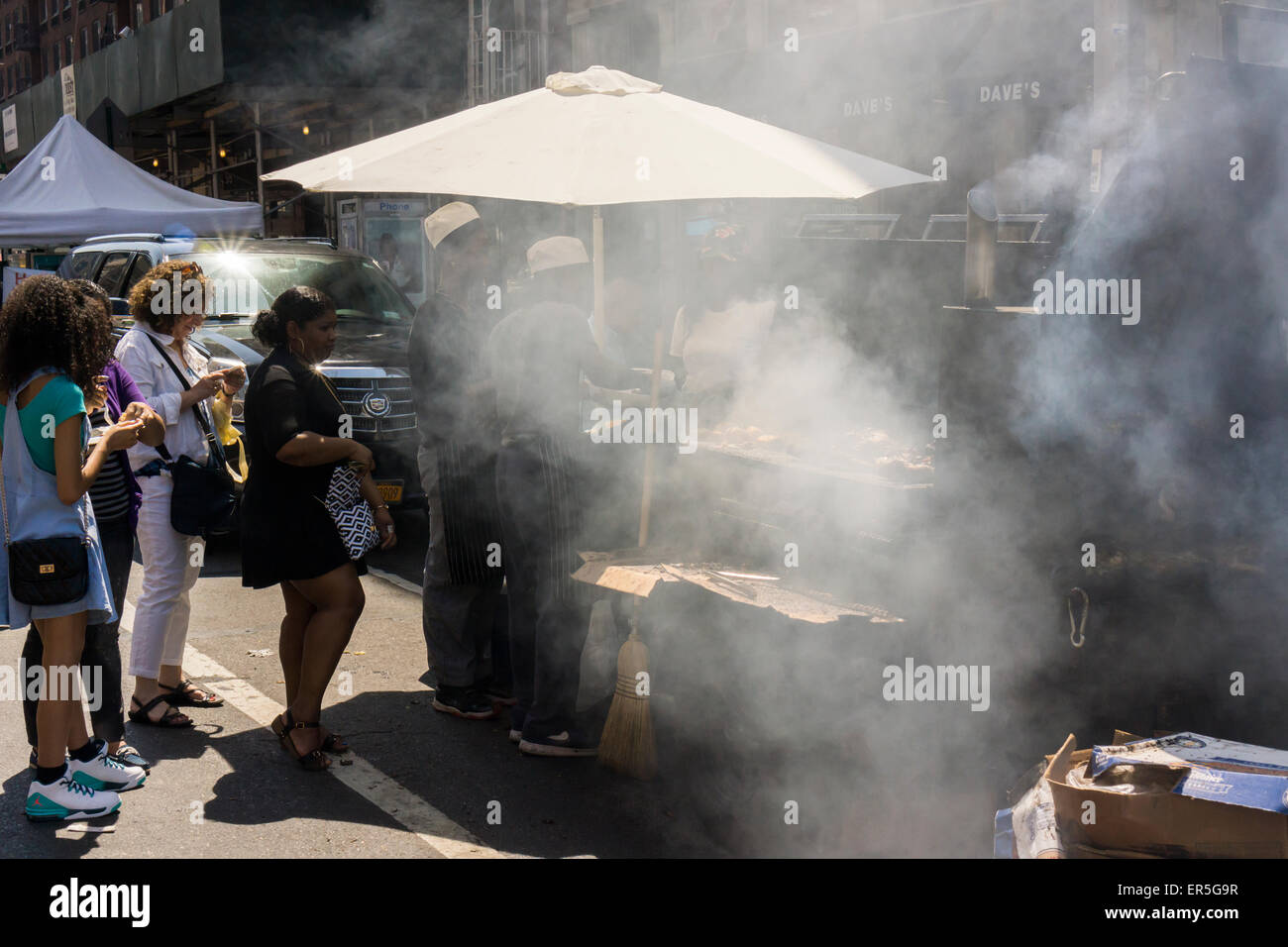 A vendor smokes jerk chicken and smokes up the air at a street fair in the Chelsea neighborhood of New York on Monday, May 25, 2015. (© Richard B. Levine) Stock Photo