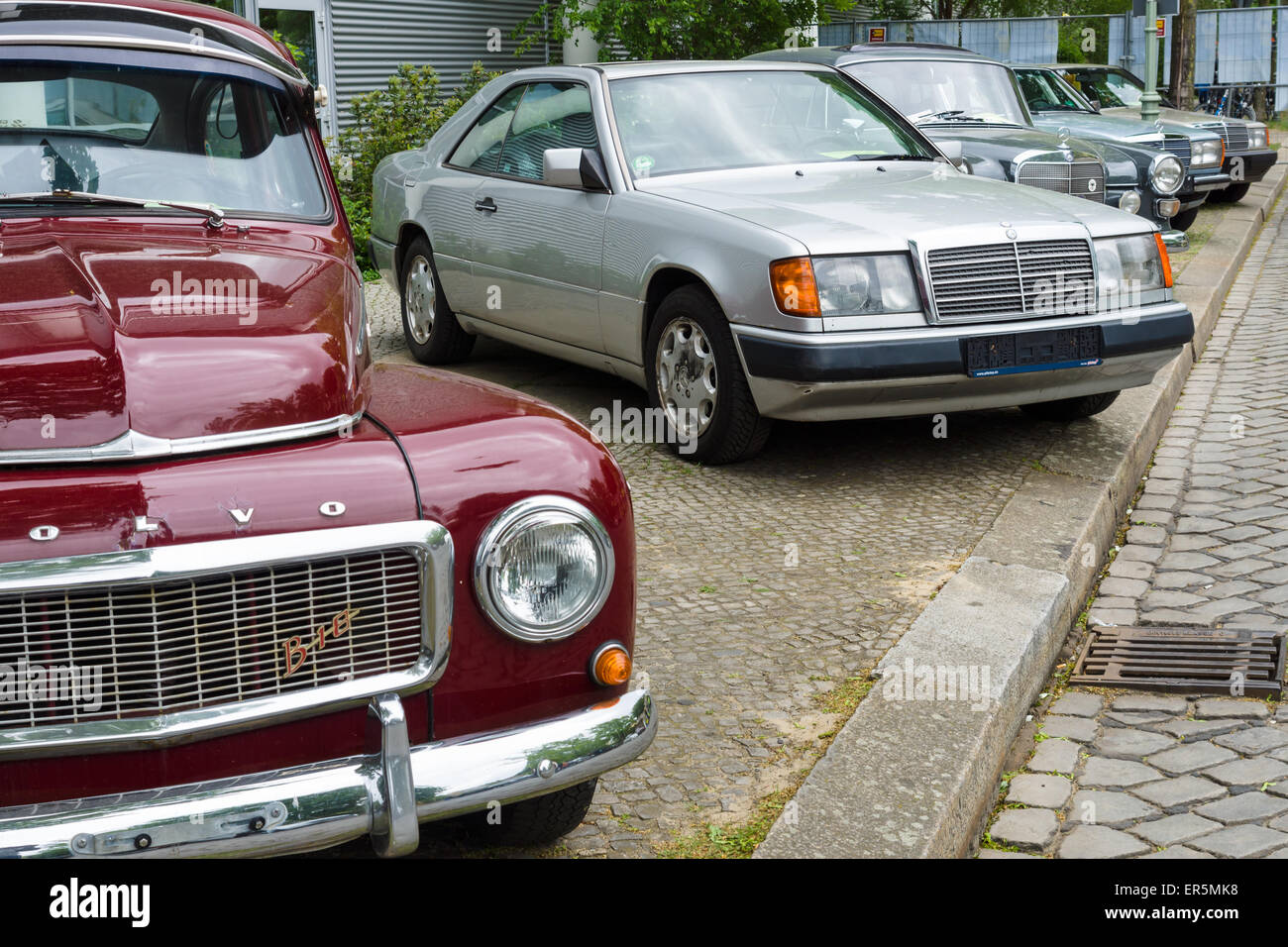 Retro cars standing in a row. In the foreground a Volvo PV544, in the background, full-size luxury car Mercedes-Benz W124 Coupe Stock Photo