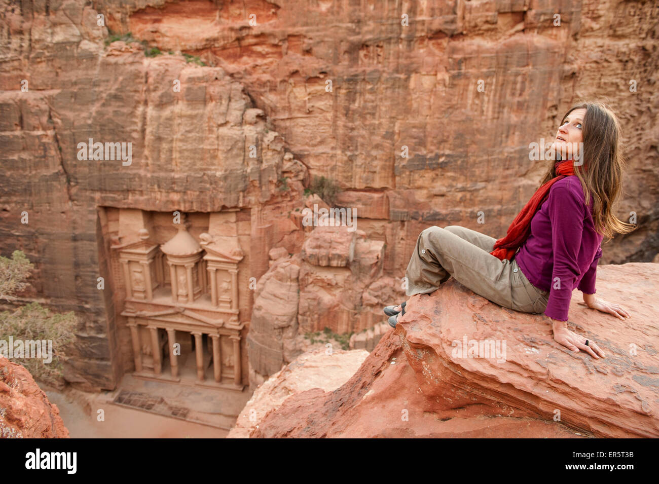 Woman sitting on a rock, Al Khazneh in background, Petra, Jordan, Middle East Stock Photo