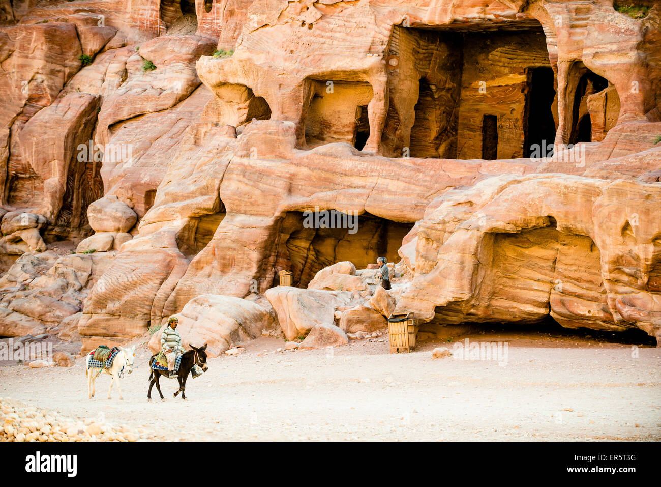 Man riding a donkey passing rock-cut tombs, Petra, Jordan, Middle East Stock Photo