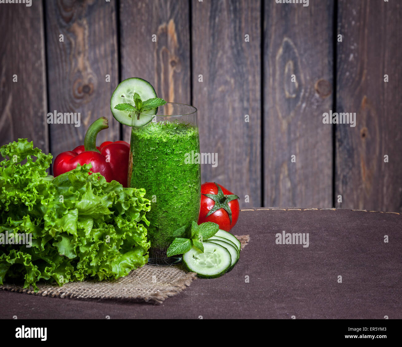 Fresh green smoothie with cucumber, green salad leaves, tomato and red capsicum at wooden background Stock Photo