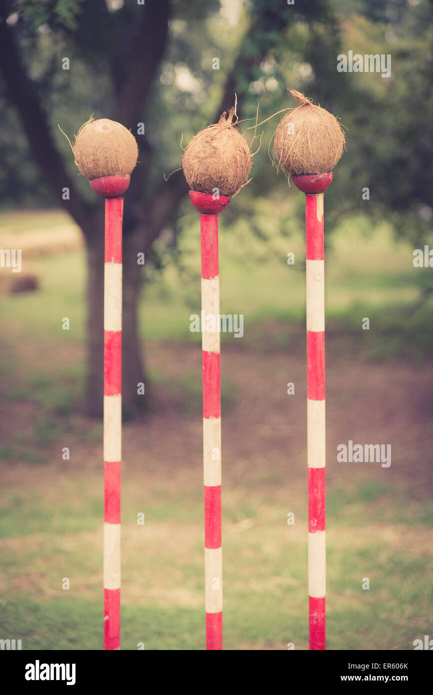 three coconuts on red and white poles forming a coconut shy at a fair.  This image has been treated with a retro film simulation Stock Photo