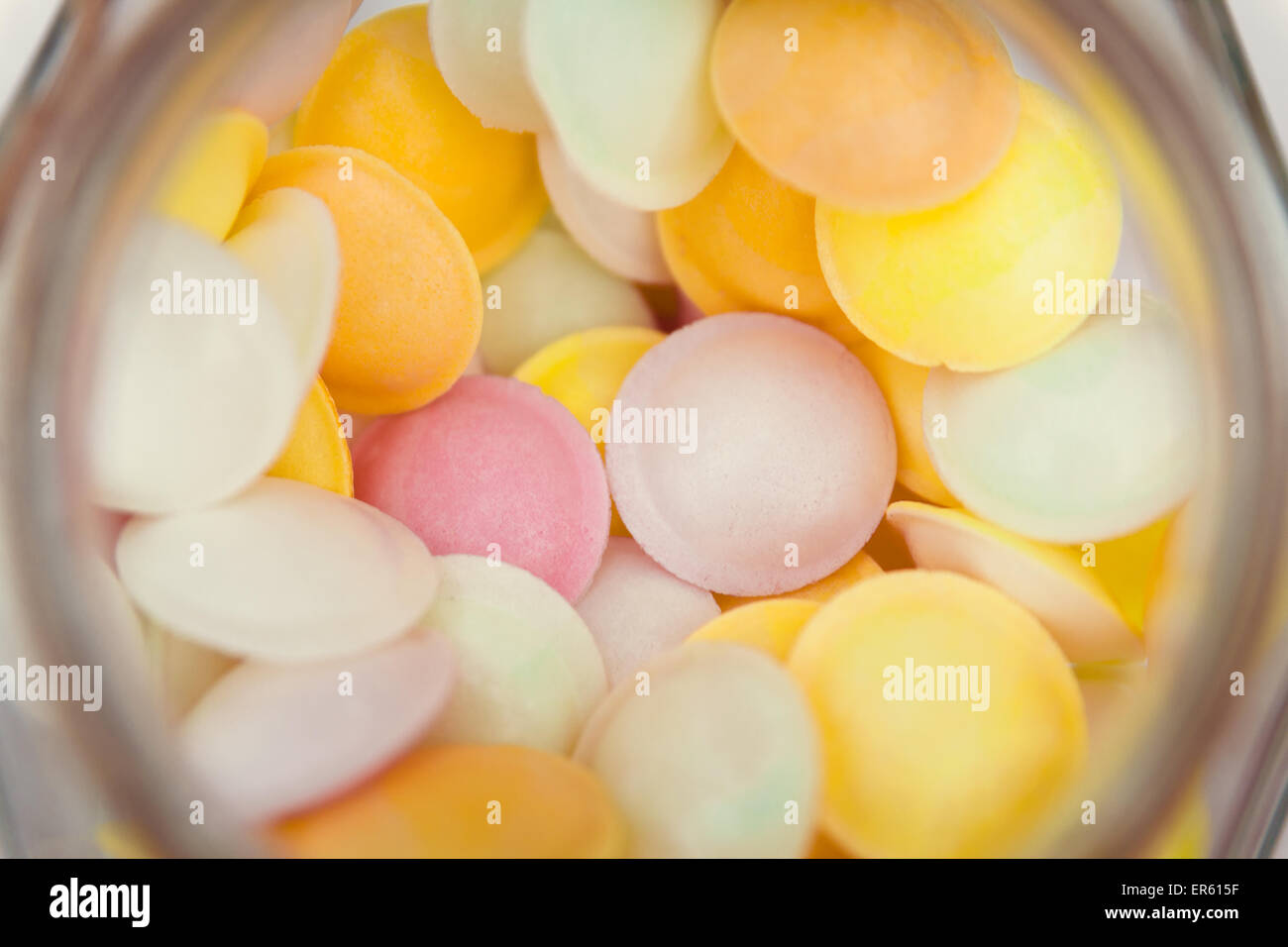 Looking down at a jar full of multi colored flying saucer sweets. The