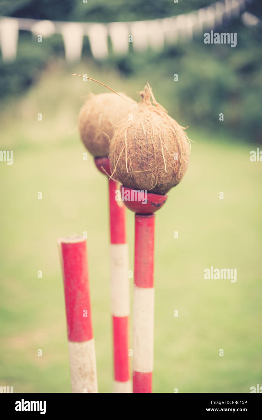 three poles forming a Coconut shy, one coconut has been knocked off.  this image has been treated with a retro film simulation. Stock Photo