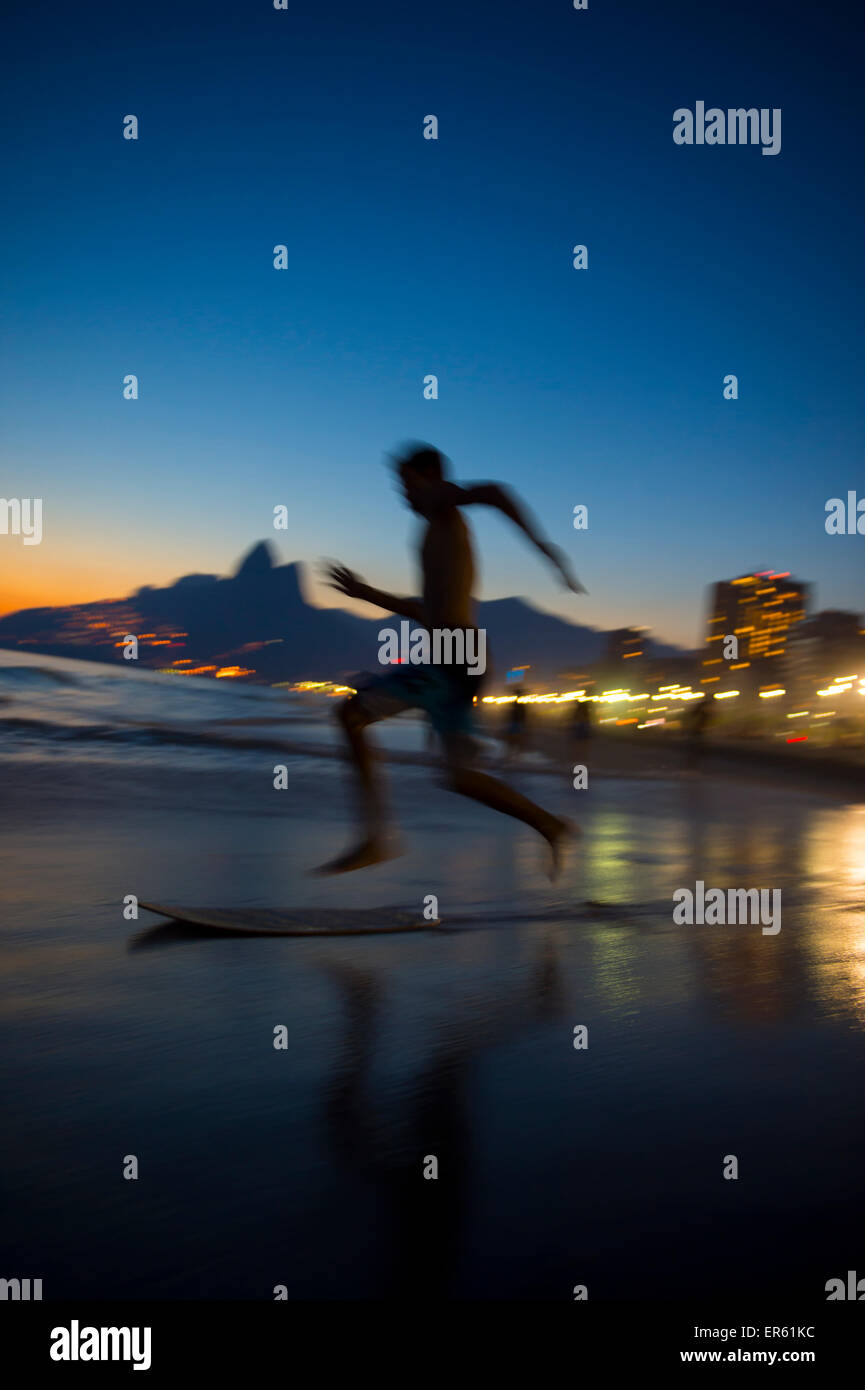 Action silhouette of Brazilian jumping onto skimboard on Ipanema Beach Rio de Janeiro Brazil at sunset Stock Photo