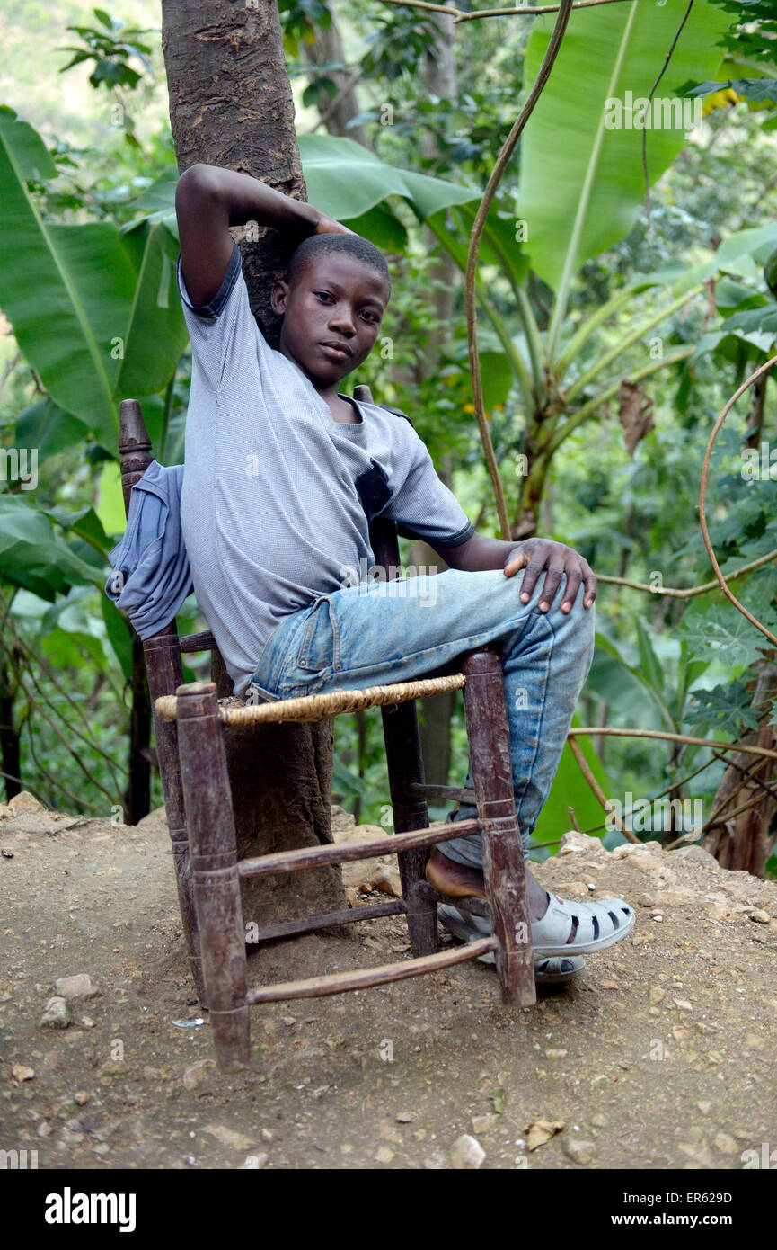 Teenager boy on a rickety chair, Riviere Froide, Ouest Department, Haiti Stock Photo
