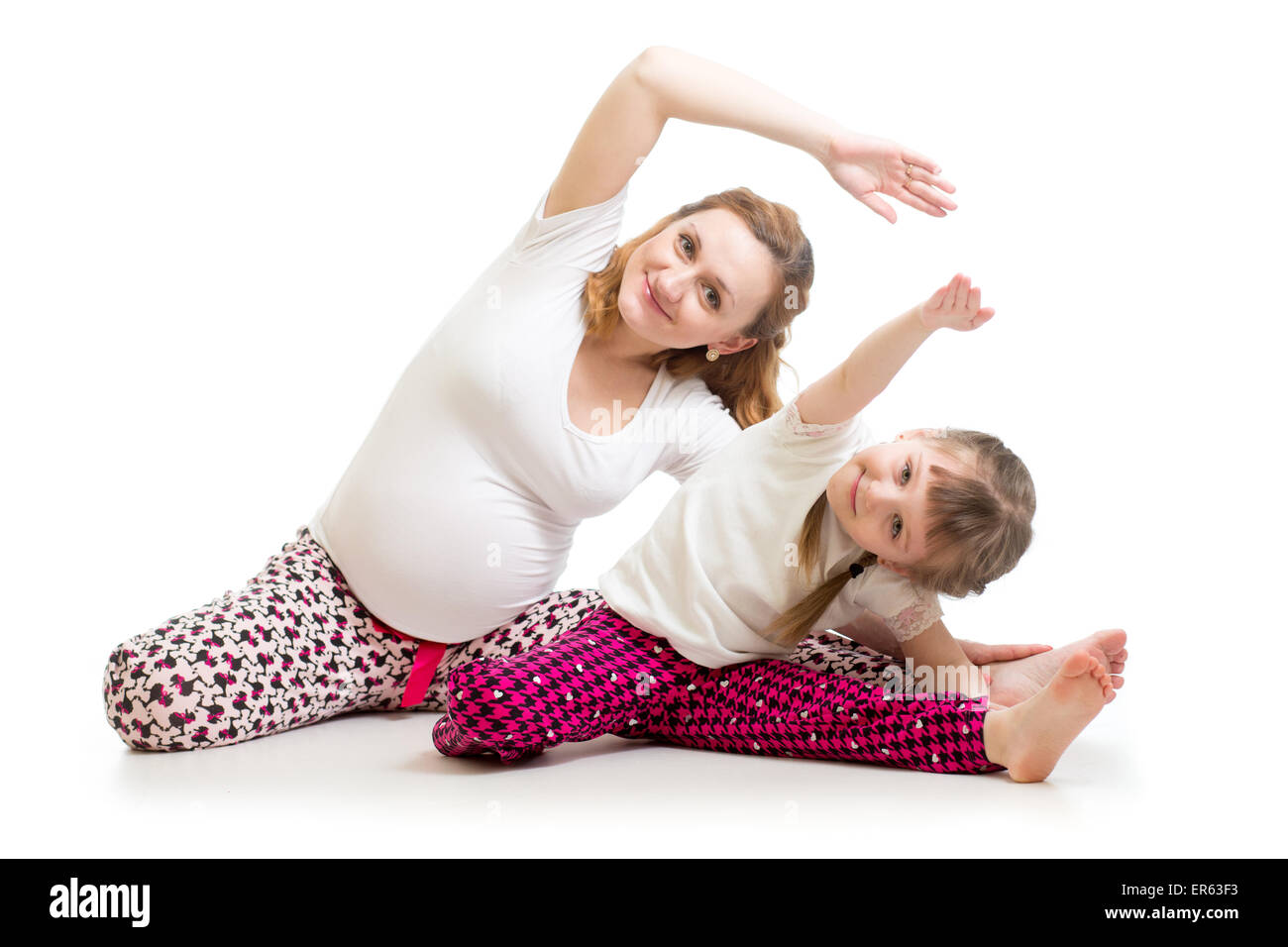 Family doing gymnastics. Pregnant woman with child daughter exercising stretching on floor Stock Photo