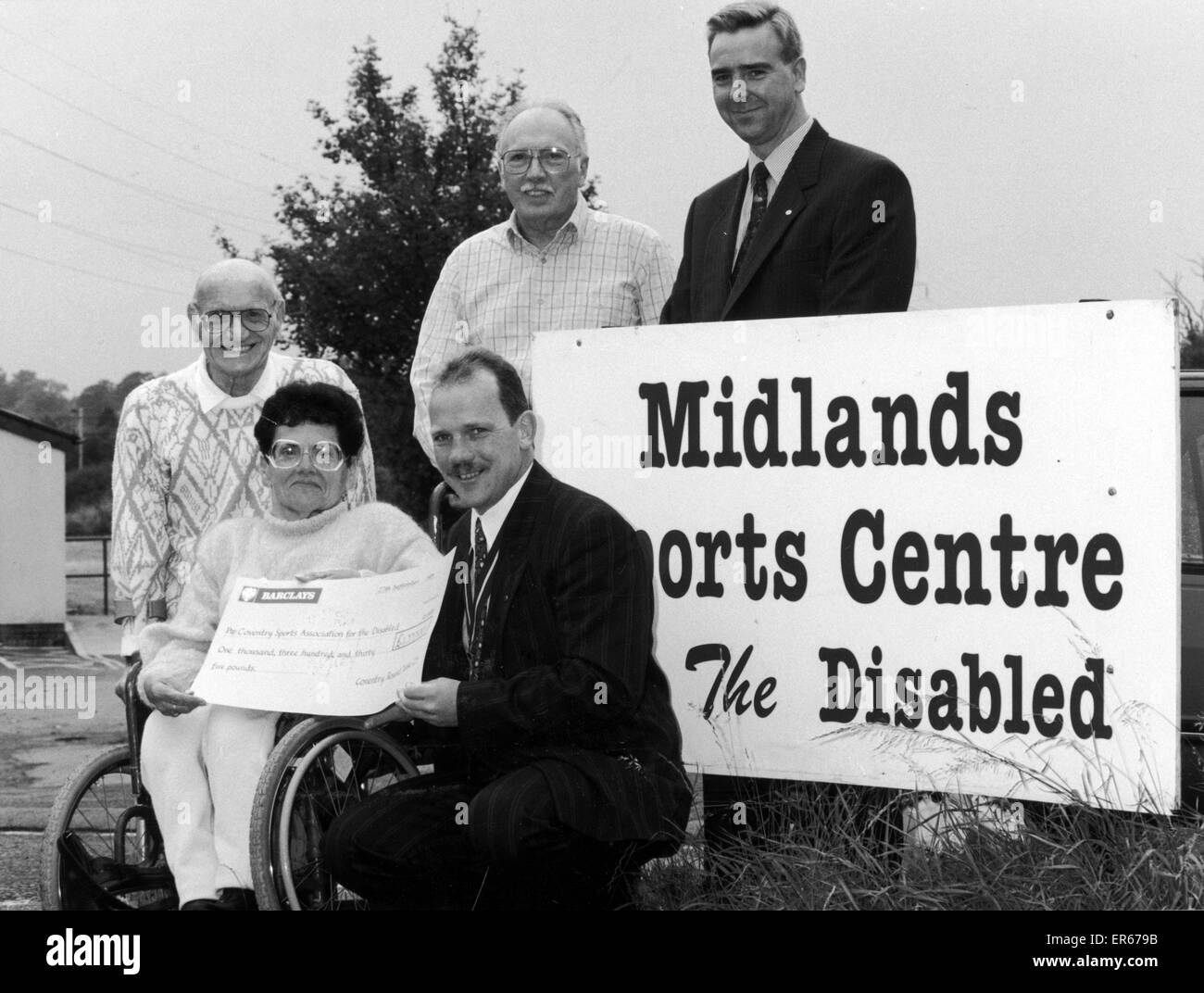 June Peer and Len Tassker (left) of the Coventry Sports Association for the Disabled, receive a cheque for ¿1,335 from Coventry Round Table vice chairman Phil Gill (front). 29th September 1993 Stock Photo