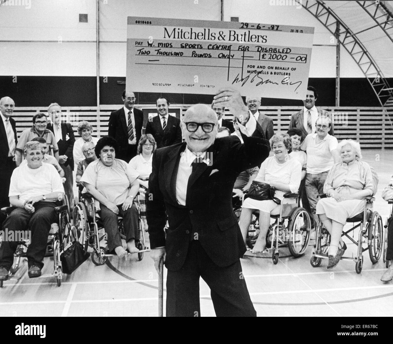 Len Tasker the trustee for the West Midlands Sports Centre for the Disabled, with a gaint cheque for the sum of ¿2000 after the presentation by Mike Bromley managing director of Mitchells and Butlers. 30th June 1987 Stock Photo