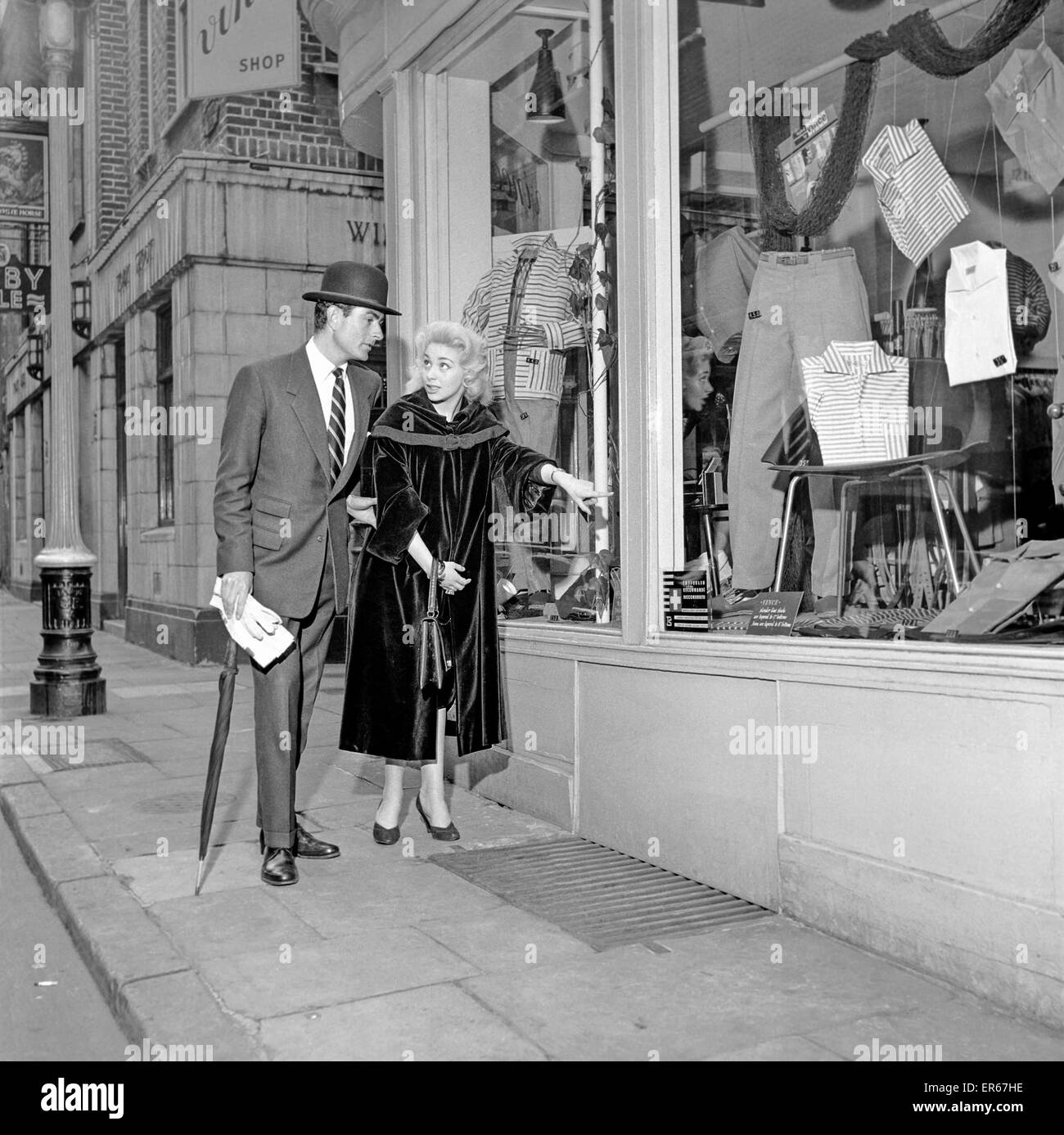 Clothing men's and women’s fashions 1957: Models Michael Stanley and Bernice Swanson try on the latest fashions at Vinci's mans shop in Newburgh street London. May 1957 A379-007 Stock Photo