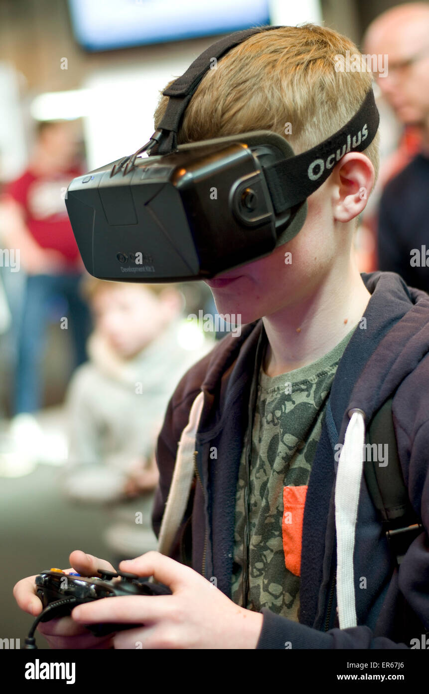 Young male wearing Oculus Rift 3D virtual reality goggles with game controller in his hands. Stock Photo