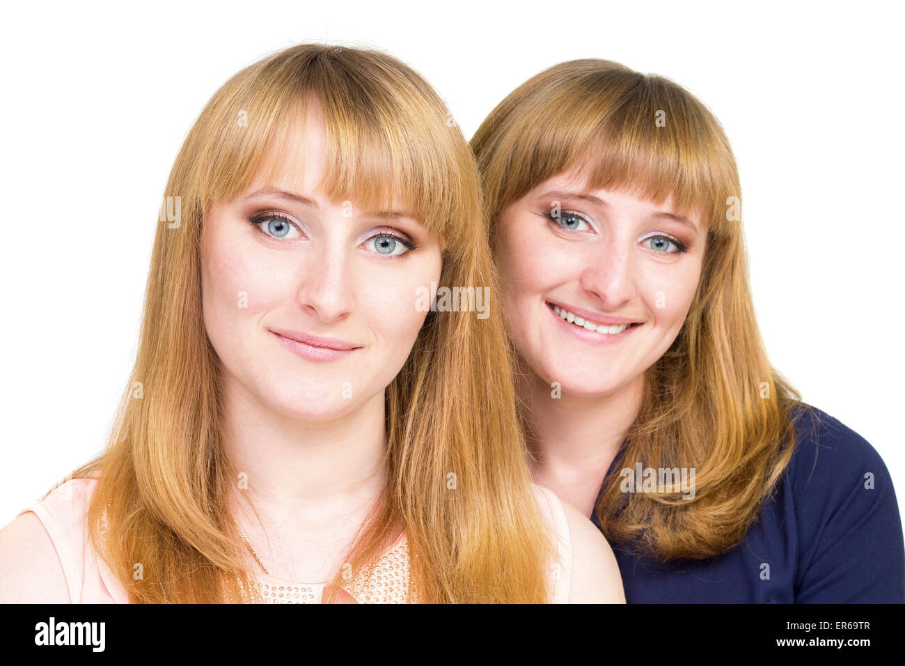 Young twins girls isolated on white background. Cheerful smiling sisters looking straight into camera Stock Photo