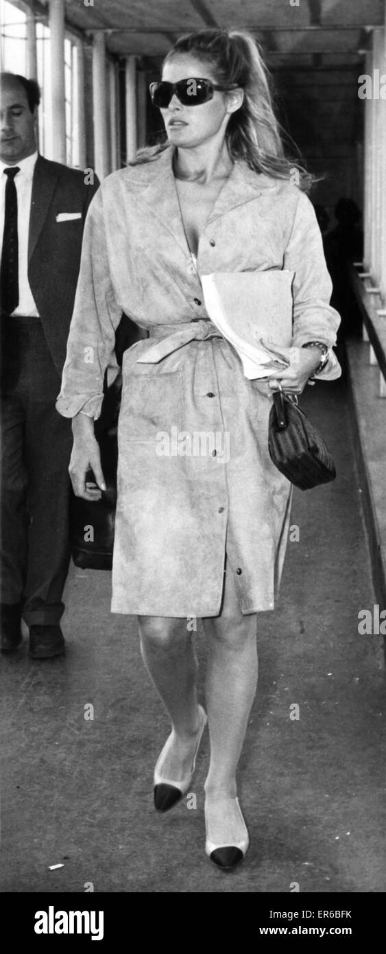 Ursula’s Flying Fashion: Actress Ursula Andress is pictured here leaving London Airport for Rome on Friday in similar fashion to her arrival on Wednesday in big, dark glasses, belted raincoat and her fair hair awry. She was here for wardrobe fittings for Stock Photo