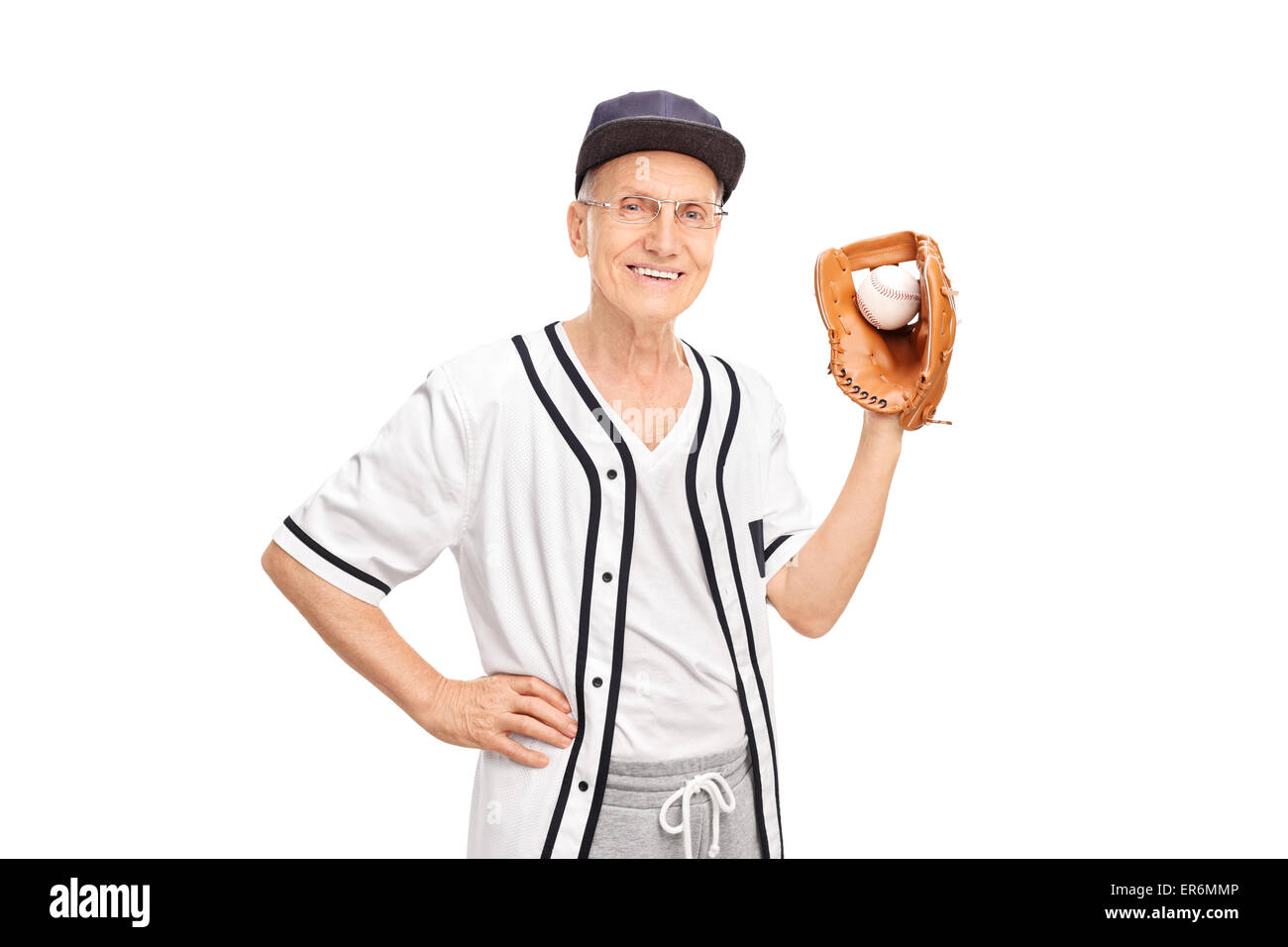 Senior man in a white baseball jersey holding a baseball and looking at the camera isolated on white background Stock Photo