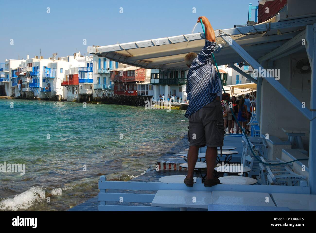 Taverna owner getting ready to open for business, Little Venice, Mykonos, Greek Islands, Greece Stock Photo