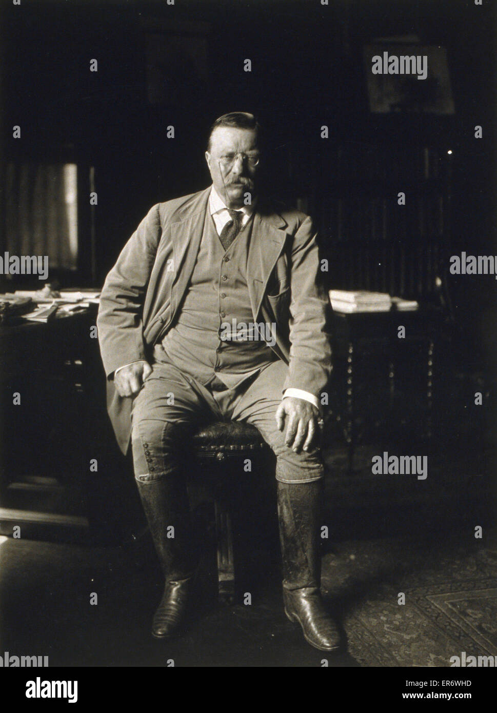 Theodore Roosevelt in his library at Oyster Bay N.Y. Theodore Roosevelt, full-length portrait, seated, facing for the front. c. 1912 Stock Photo