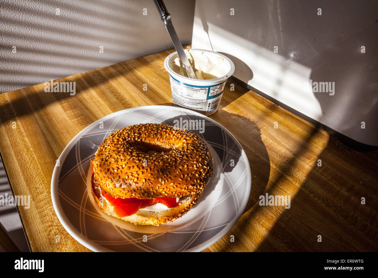 A sesame seed bagel with cream cheese and smoked salmon in the early