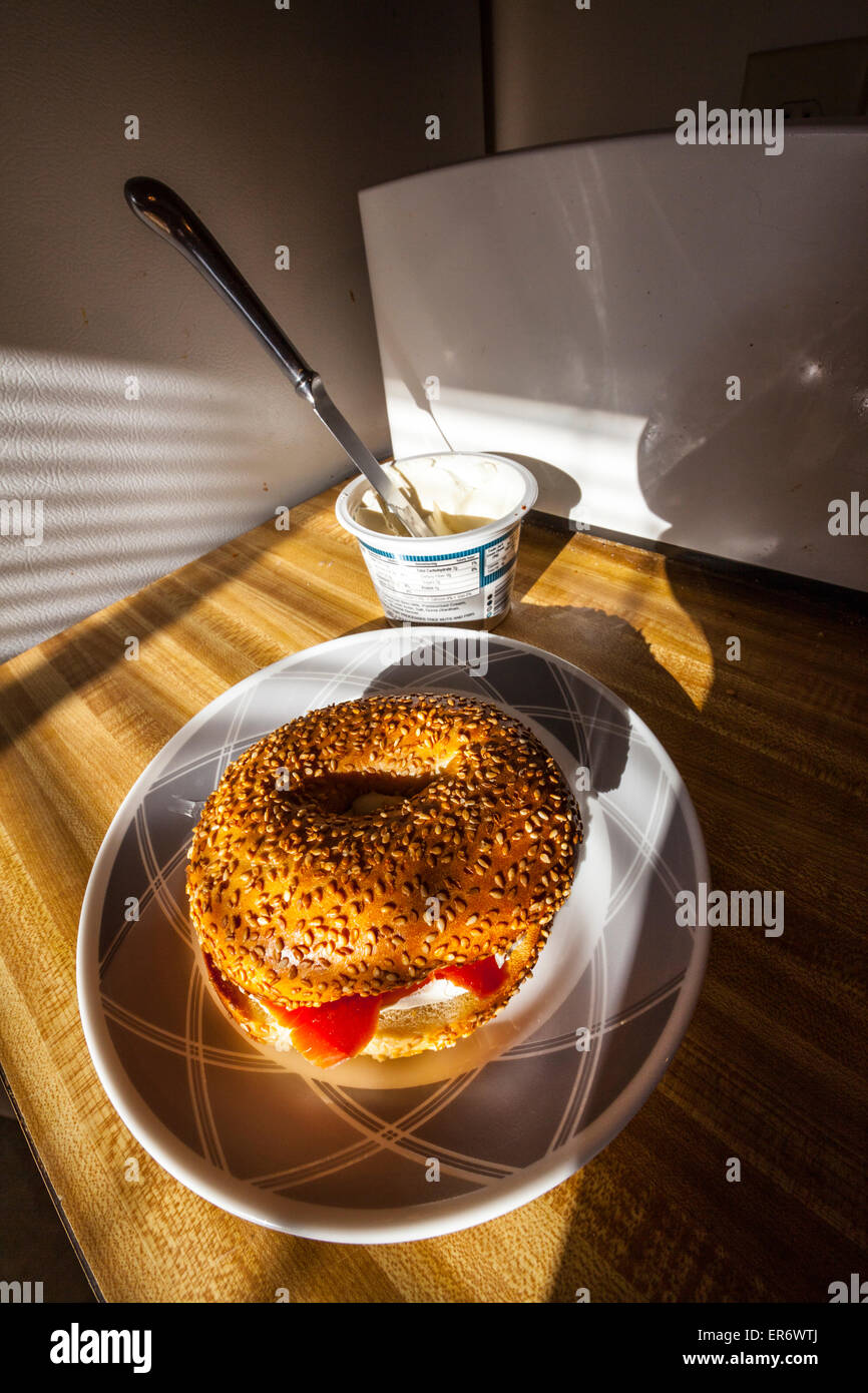 A sesame seed bagel with cream cheese and smoked salmon in the early